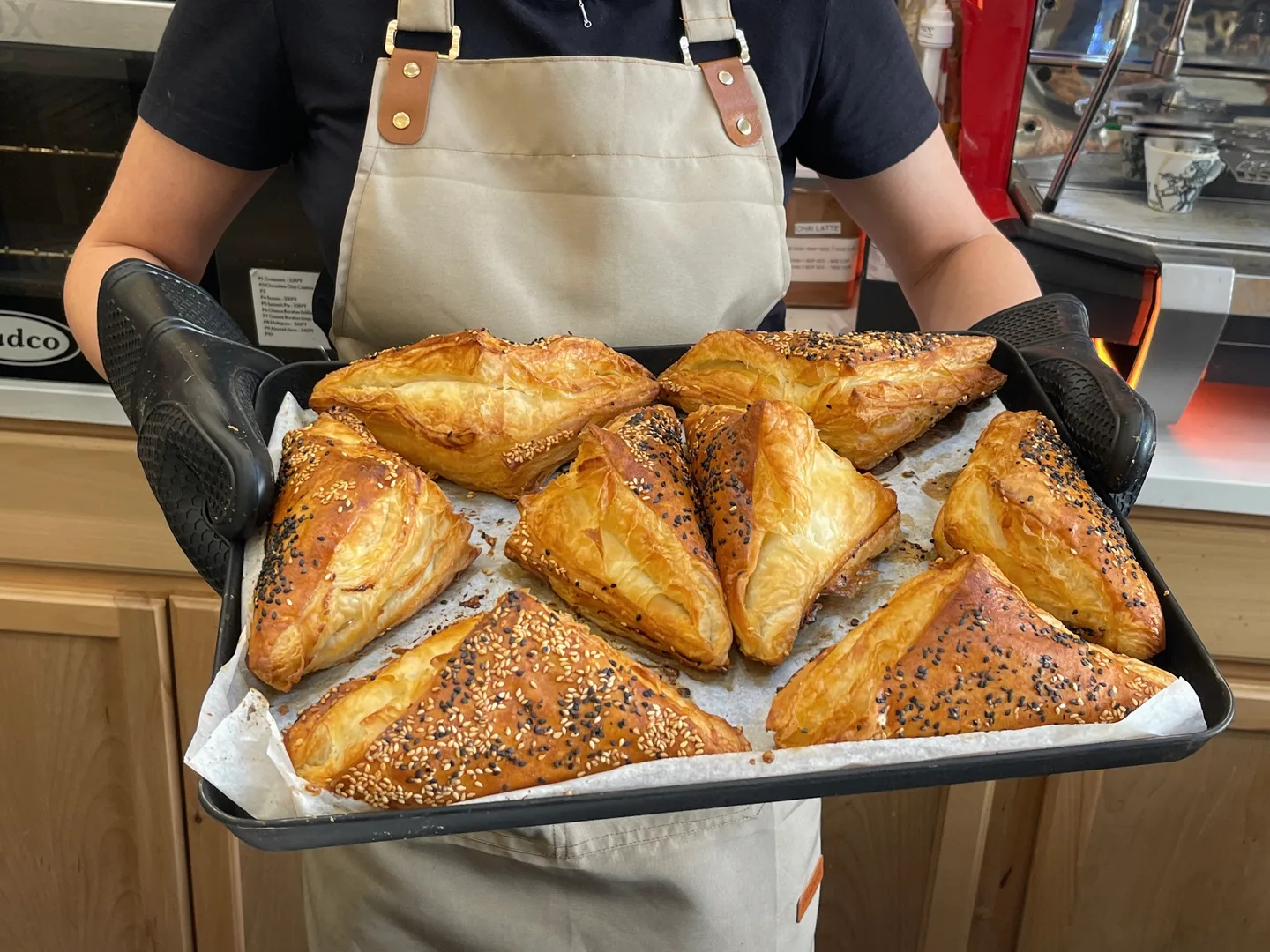 A Matto team member holding a tray of freshly baked golden pastries
