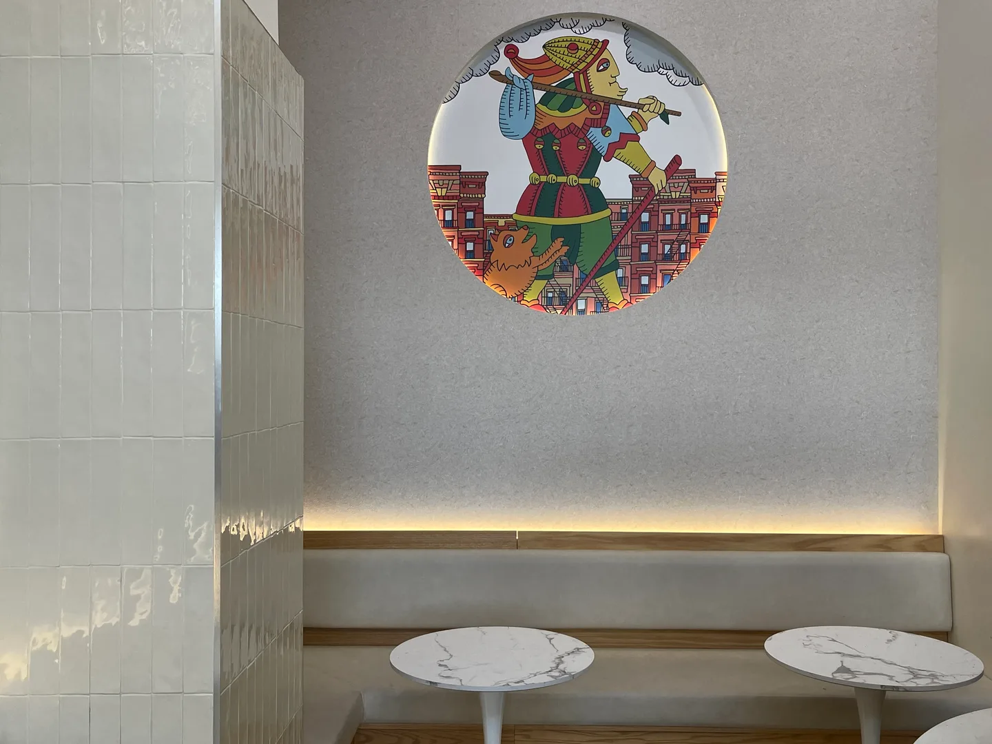 Matto character artwork above a café bench and small marble tables